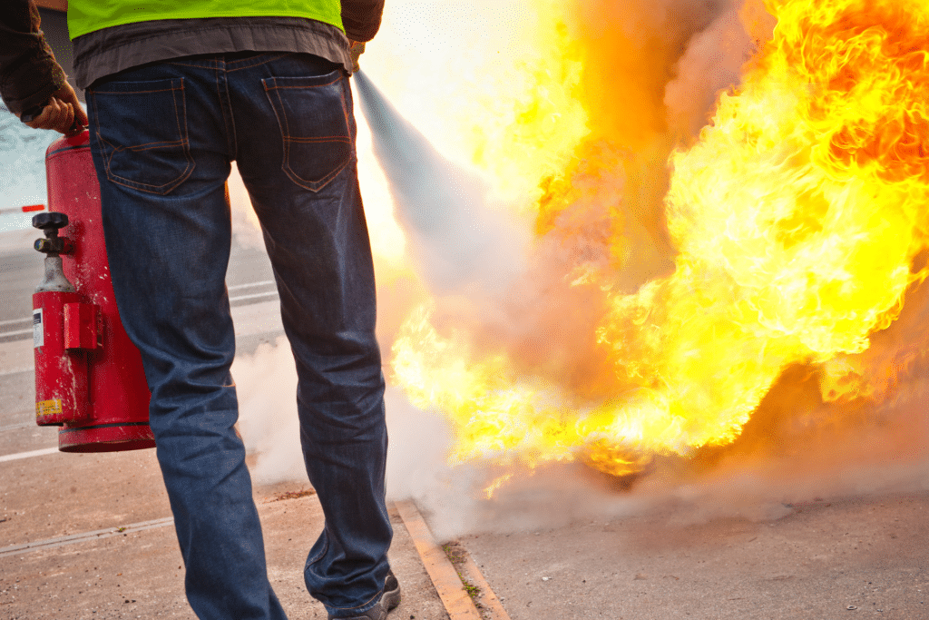 Homme éteignant un feu en extérieur avec un extincteur