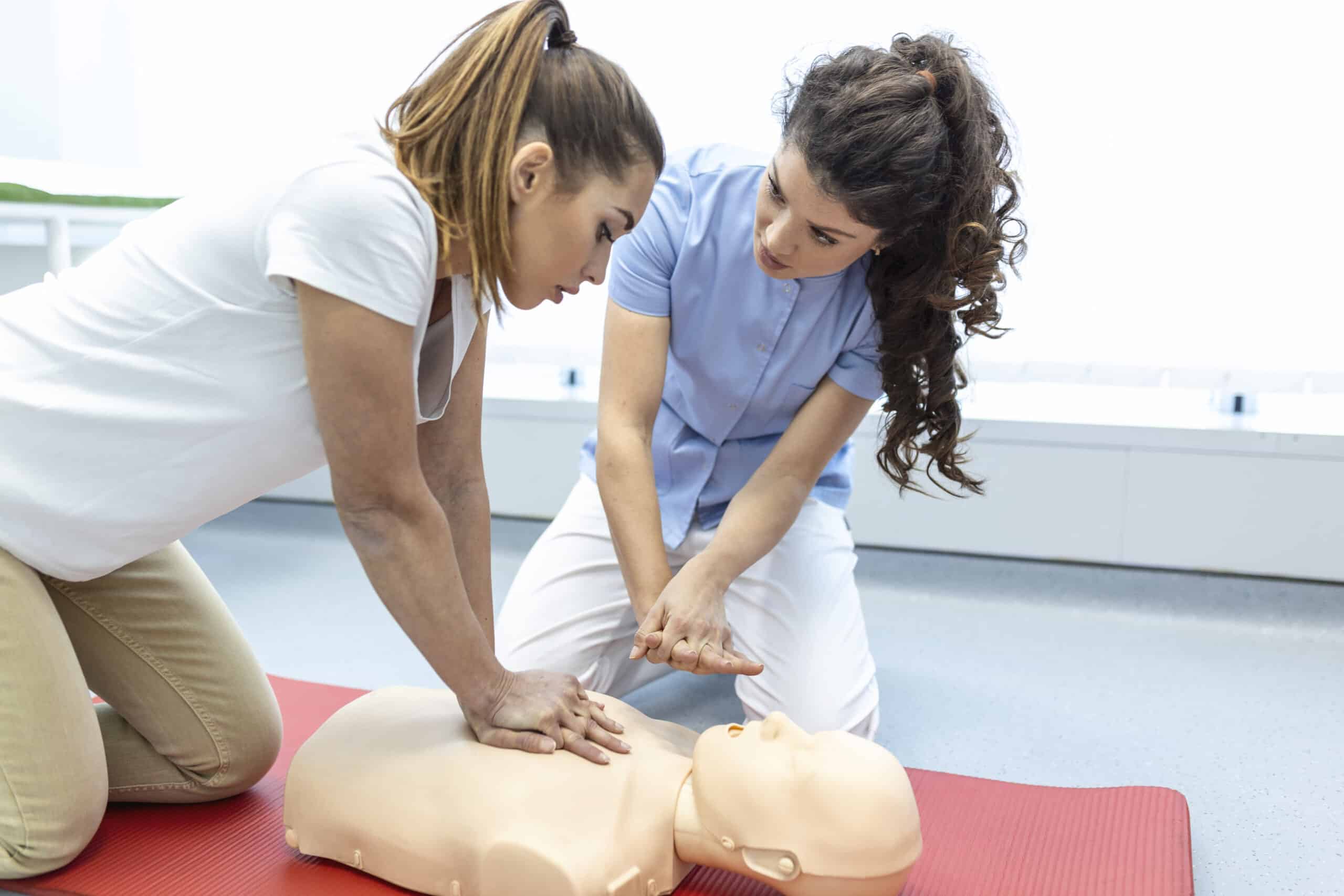 Cours de RCP avec des instructeurs qui expliquent et démontrent les premiers secours, les compressions et la procédure de réanimation. Mannequin de RCP