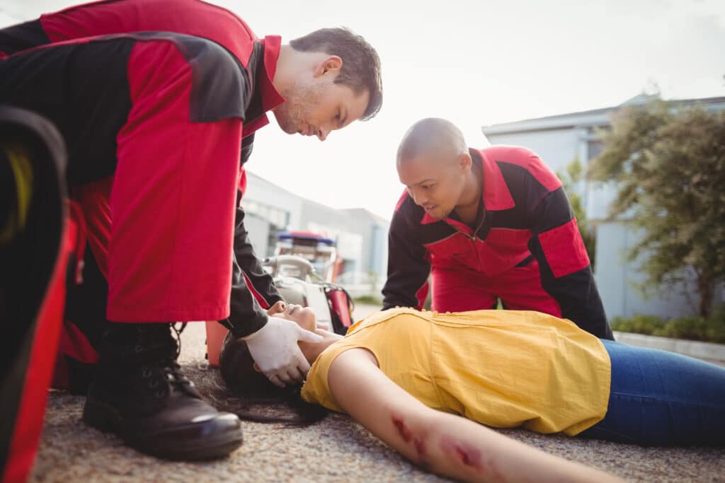 Des ambulanciers examinent une femme blessée dans la rue.